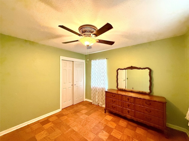 bedroom with a textured ceiling, a closet, light parquet floors, and ceiling fan