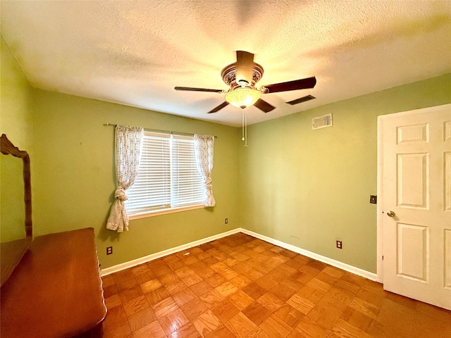 unfurnished room with ceiling fan and a textured ceiling