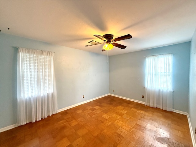 spare room featuring ceiling fan, plenty of natural light, and light parquet floors