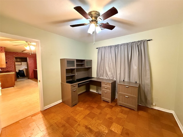 home office featuring ceiling fan, brick wall, and light wood-type flooring