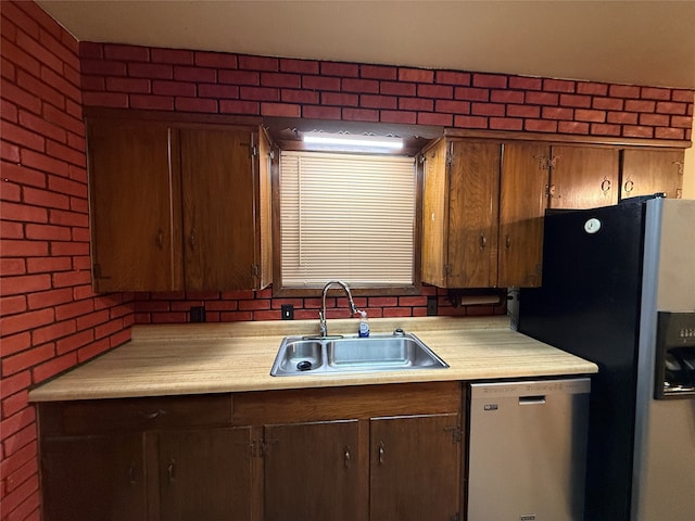 kitchen featuring sink, stainless steel appliances, and brick wall