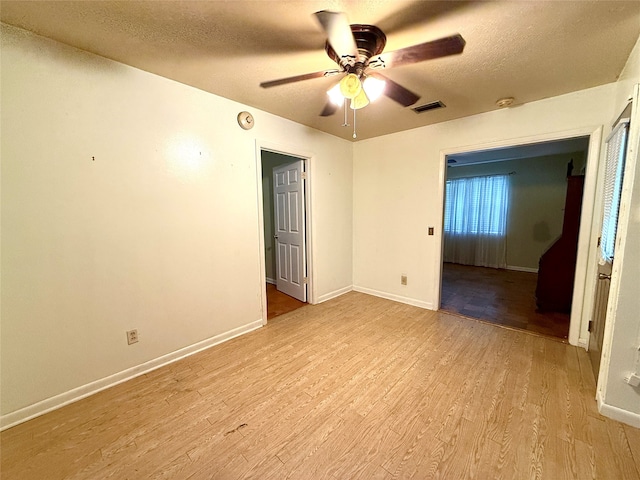 spare room featuring a textured ceiling, light hardwood / wood-style flooring, and ceiling fan