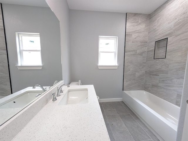 bathroom featuring vanity, tiled shower / bath, and a healthy amount of sunlight