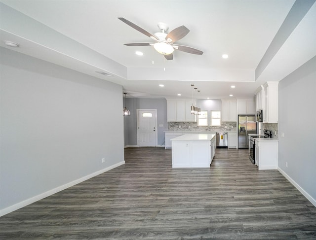 kitchen with pendant lighting, white cabinetry, stainless steel appliances, tasteful backsplash, and a kitchen island