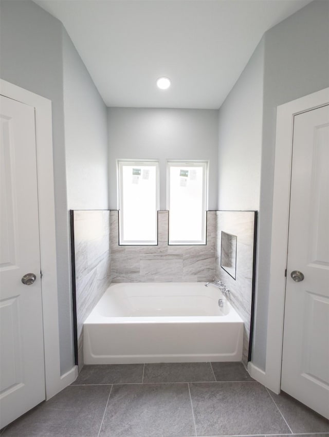 bathroom with tile patterned floors, a tub, and tile walls