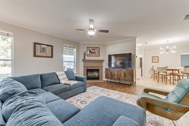 living room featuring ornamental molding, ceiling fan with notable chandelier, and light hardwood / wood-style floors