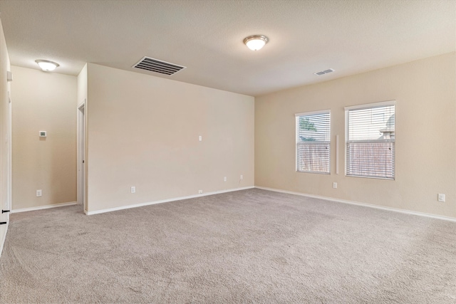 carpeted empty room featuring a textured ceiling