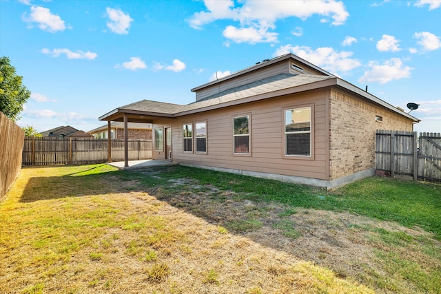 back of property with a yard and a patio