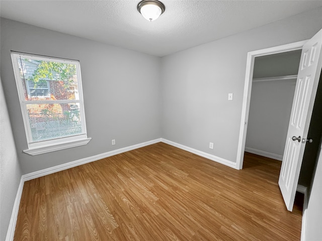 unfurnished bedroom with a closet, a walk in closet, and light wood-type flooring