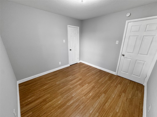 empty room with a textured ceiling and hardwood / wood-style flooring