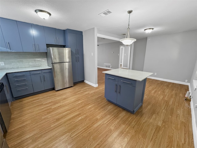 kitchen featuring blue cabinetry, a center island, decorative light fixtures, and stainless steel refrigerator