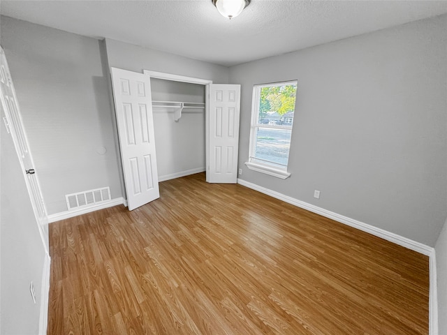 unfurnished bedroom featuring a closet, a textured ceiling, and light wood-type flooring