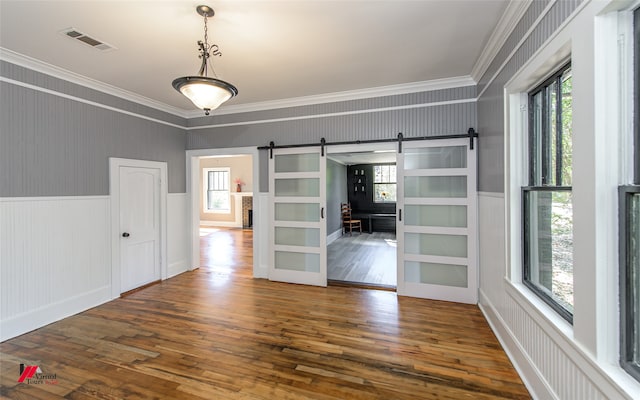 empty room with ornamental molding, a barn door, and dark hardwood / wood-style flooring