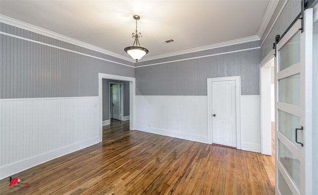 unfurnished room with dark wood-type flooring, ornamental molding, and a barn door