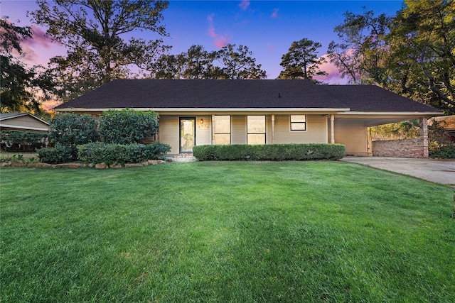 ranch-style home featuring a lawn, an attached carport, and concrete driveway