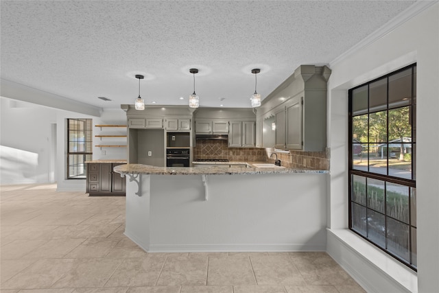 kitchen featuring oven, kitchen peninsula, gray cabinetry, crown molding, and decorative light fixtures