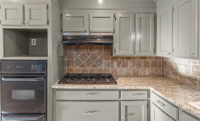 kitchen featuring under cabinet range hood, oven, a warming drawer, gas stovetop, and backsplash