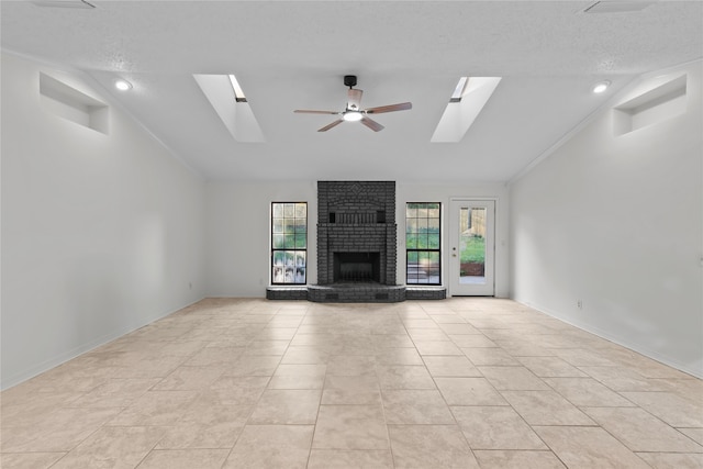 unfurnished living room with vaulted ceiling with skylight, a textured ceiling, ceiling fan, and a brick fireplace