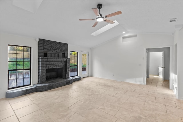 unfurnished living room with ceiling fan, visible vents, baseboards, a fireplace, and lofted ceiling with skylight