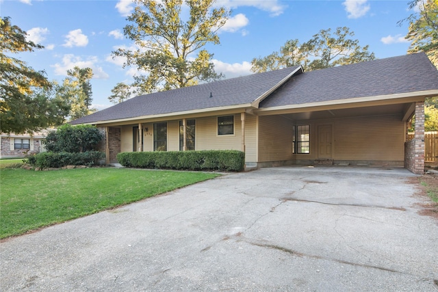 single story home featuring a carport, a front lawn, concrete driveway, and roof with shingles