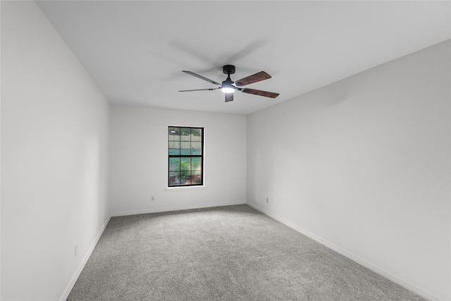 carpeted spare room featuring a ceiling fan and baseboards