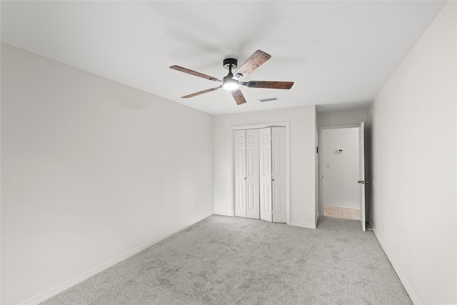 unfurnished bedroom featuring a closet, light colored carpet, and ceiling fan