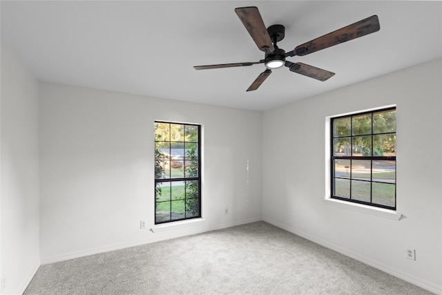 carpeted spare room featuring ceiling fan, baseboards, and plenty of natural light