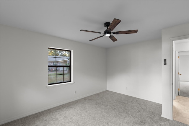 empty room with a ceiling fan, light colored carpet, and baseboards