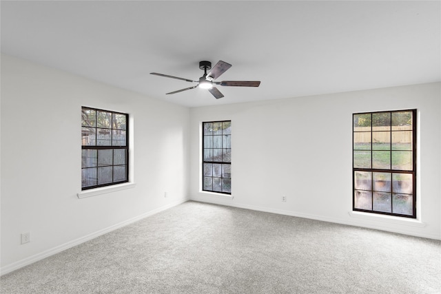 carpeted spare room featuring baseboards and a ceiling fan