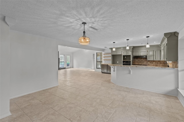 kitchen featuring light stone countertops, black oven, backsplash, a peninsula, and a kitchen breakfast bar