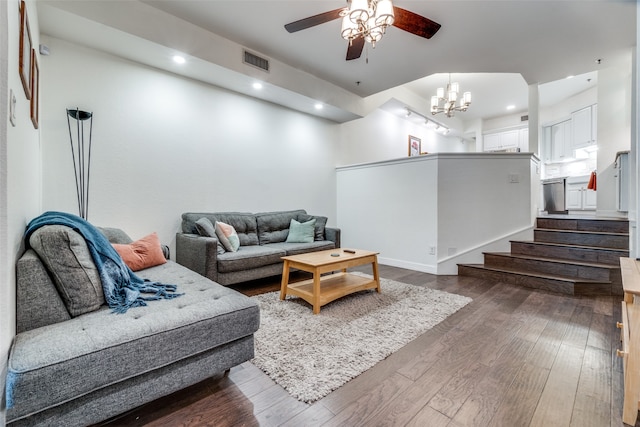 living room featuring dark wood-type flooring and ceiling fan with notable chandelier