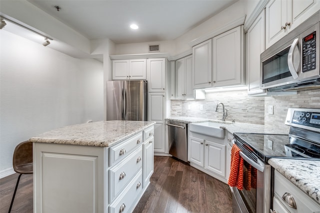 kitchen featuring stainless steel appliances, dark wood-type flooring, sink, white cabinetry, and a kitchen island