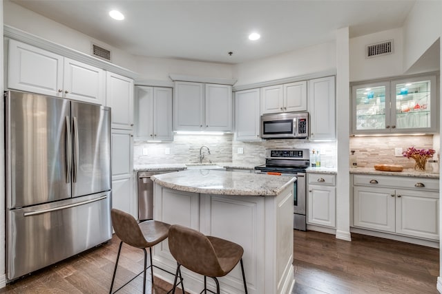 kitchen featuring white cabinets, sink, light stone countertops, appliances with stainless steel finishes, and a kitchen island