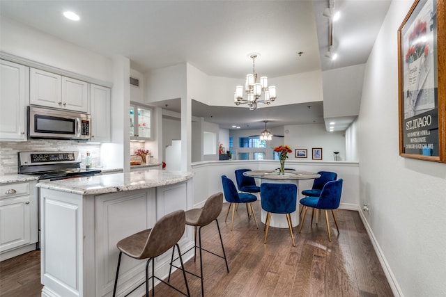 kitchen with stainless steel appliances, white cabinets, a notable chandelier, backsplash, and a kitchen island