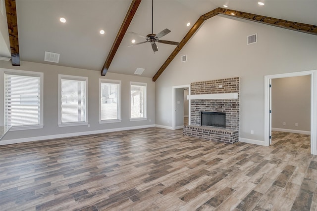 unfurnished living room with light wood-type flooring, a brick fireplace, ceiling fan, beamed ceiling, and high vaulted ceiling