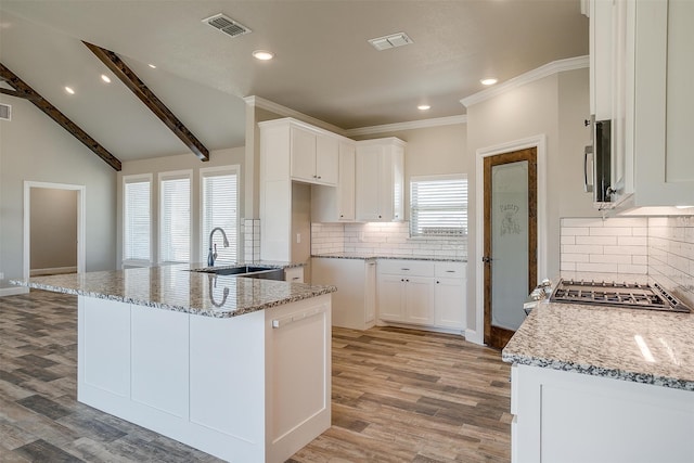 kitchen with sink, white cabinets, light stone counters, and a healthy amount of sunlight