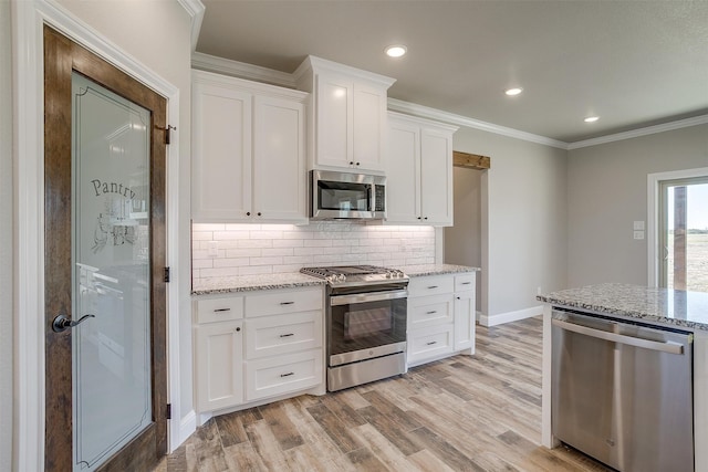 kitchen with white cabinetry, light stone counters, stainless steel appliances, and light hardwood / wood-style floors