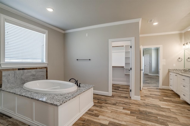 bathroom with vanity, crown molding, a bathtub, and hardwood / wood-style flooring