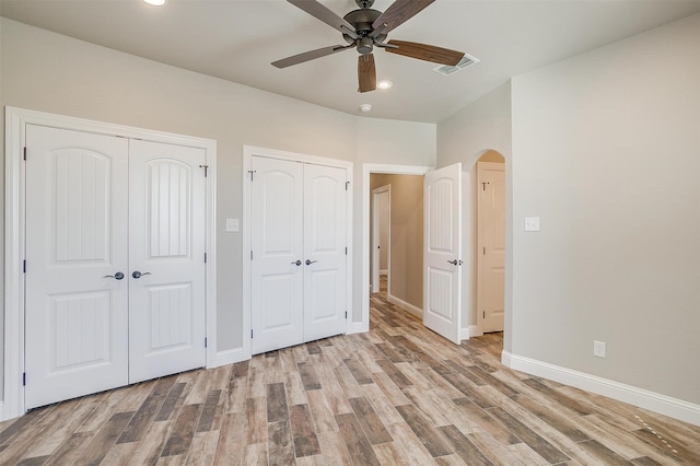 unfurnished bedroom featuring two closets, light wood-type flooring, and ceiling fan