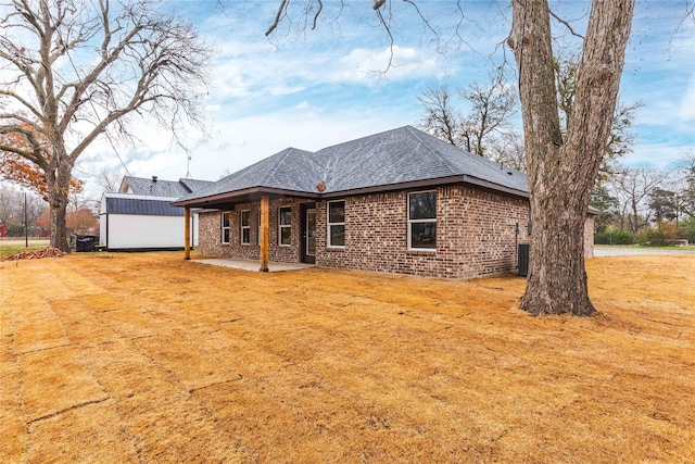 rear view of property featuring a lawn, central air condition unit, and a patio