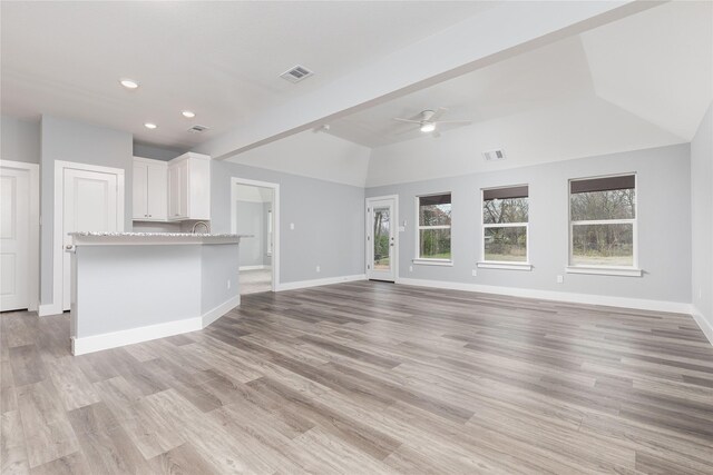 unfurnished living room with vaulted ceiling with beams, ceiling fan, and light wood-type flooring