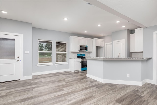 kitchen featuring white cabinets, appliances with stainless steel finishes, light hardwood / wood-style flooring, and light stone countertops