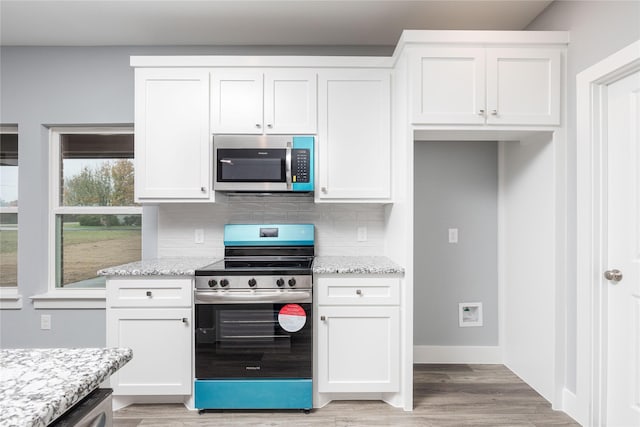 kitchen with light stone counters, white cabinetry, and stainless steel appliances