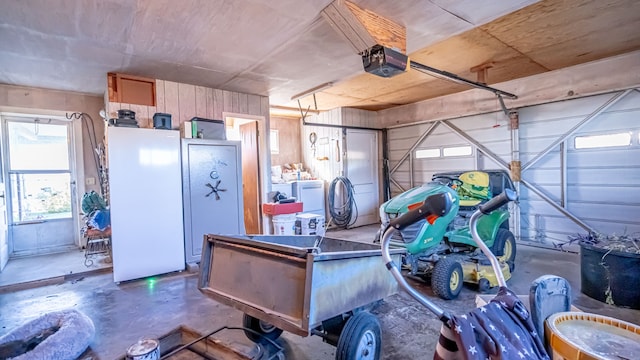 garage with washer and dryer, a garage door opener, white fridge, and wooden walls