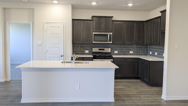 kitchen with decorative backsplash, appliances with stainless steel finishes, a kitchen island with sink, and sink