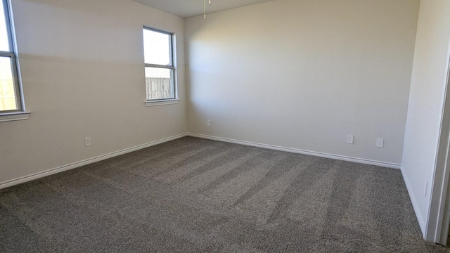 spare room with dark colored carpet