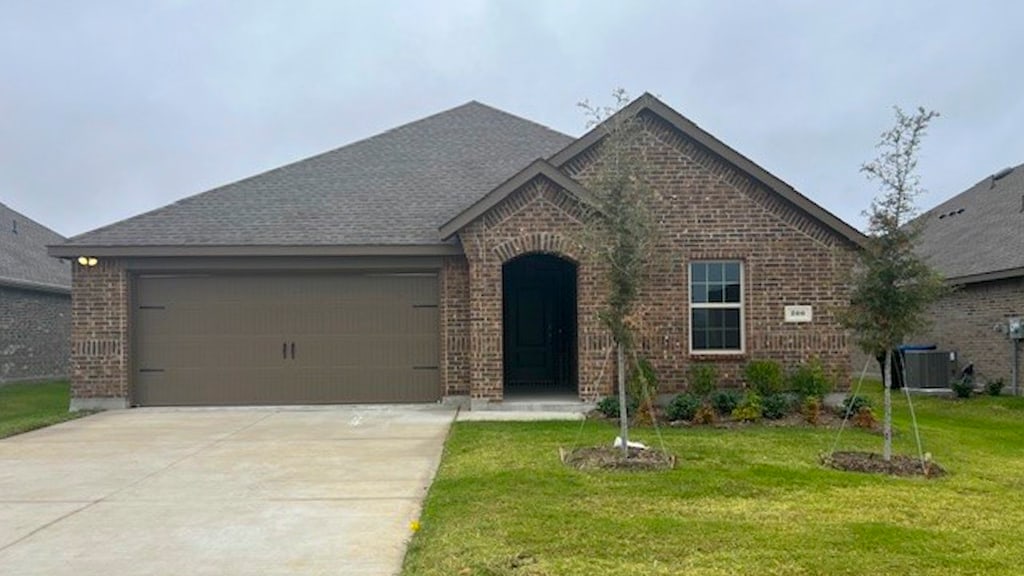 view of front of home with a garage, cooling unit, and a front yard