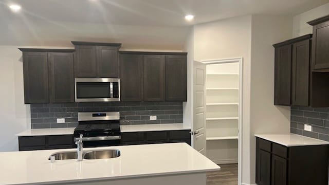 kitchen featuring hardwood / wood-style flooring, sink, backsplash, dark brown cabinets, and appliances with stainless steel finishes