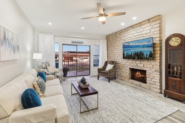 living room featuring light hardwood / wood-style flooring, ornamental molding, a fireplace, and ceiling fan