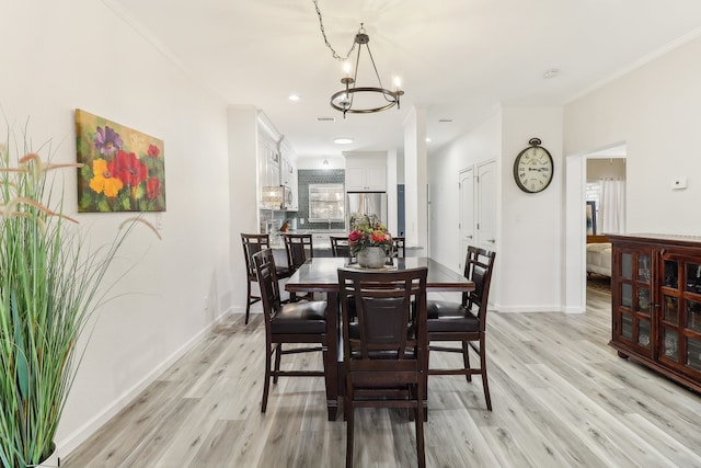 dining space featuring light hardwood / wood-style floors, crown molding, and a chandelier